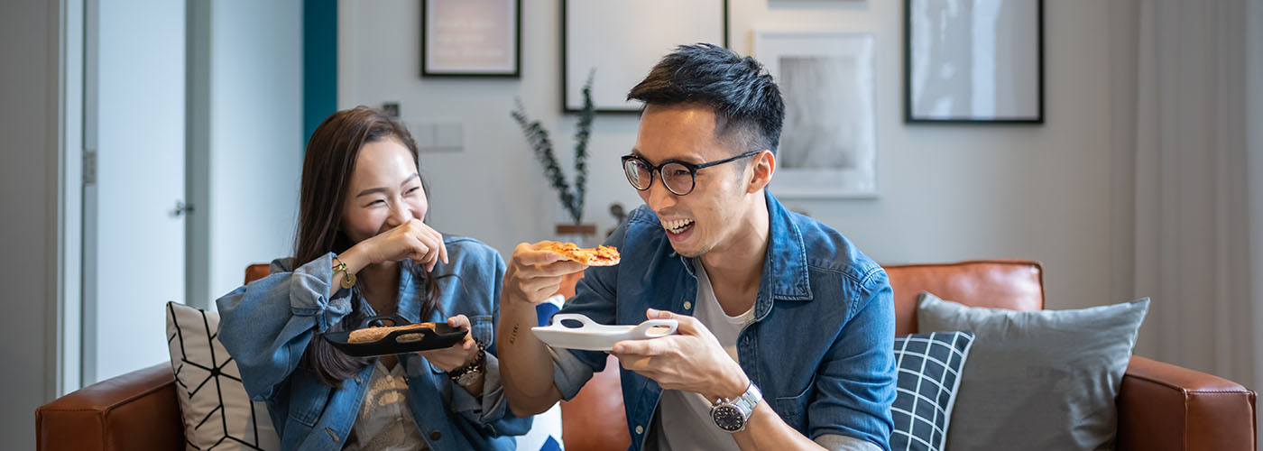 A smiling man and woman enjoy pizza, illustrating the lifestyle after successful gastroenterology care.