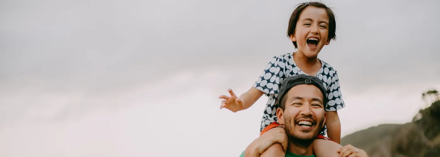 Father carrying his son on his shoulders, both smiling and enjoying their time outdoors