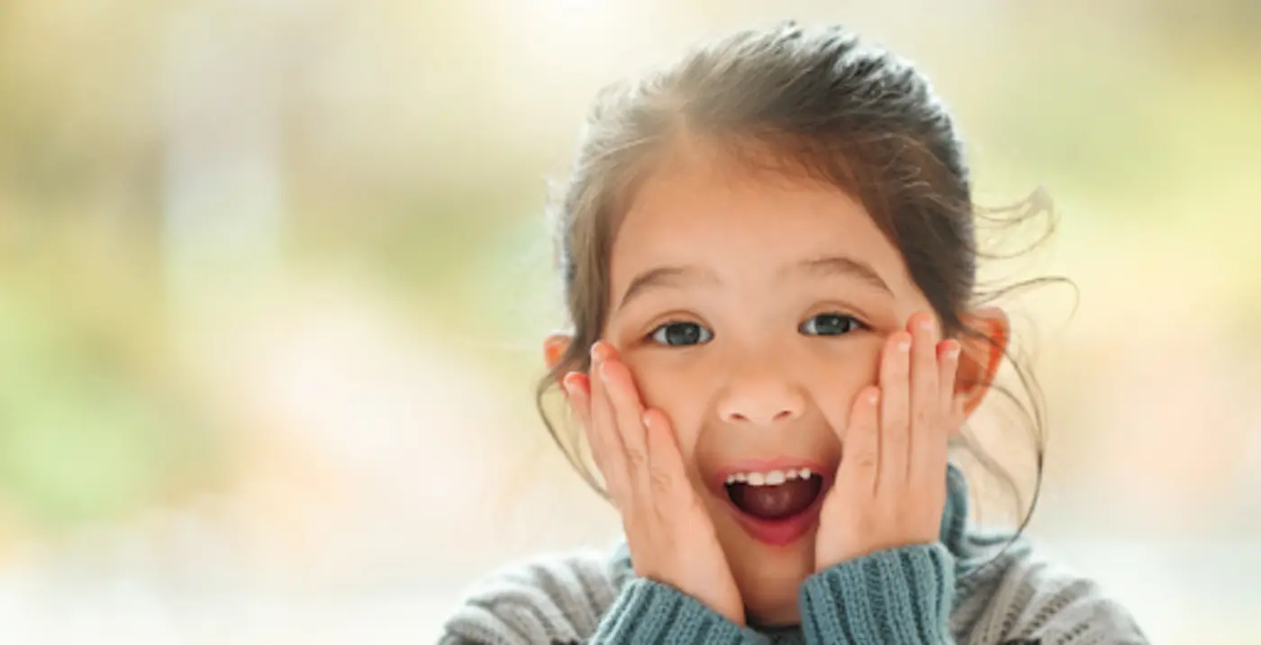 Seorang kanak-kanak memegang pipinya, melambangkan gusi yang sihat dan penjagaan mulut yang baik.