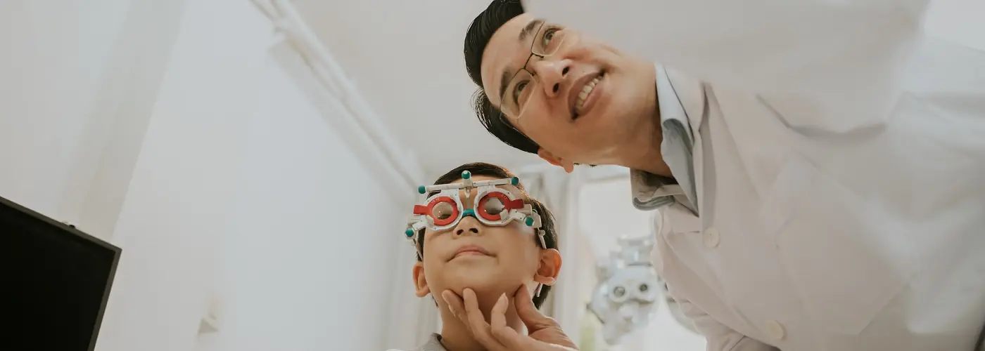 An eye specialist examining a boy's eye vision using specialised equipment in a clinic