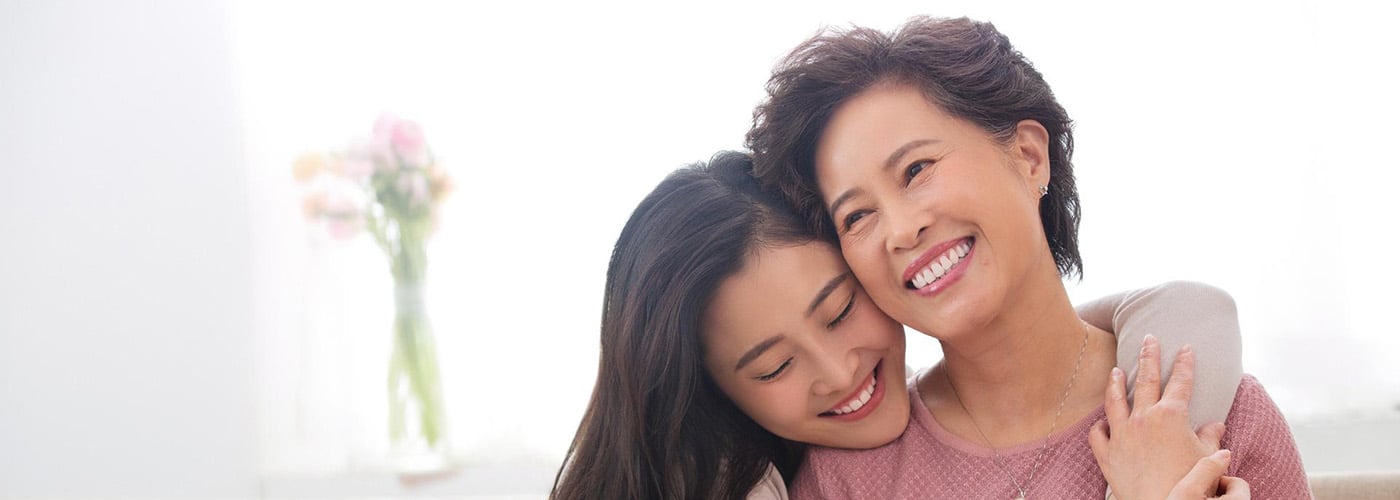 Asian mother and daughter smiling and embracing